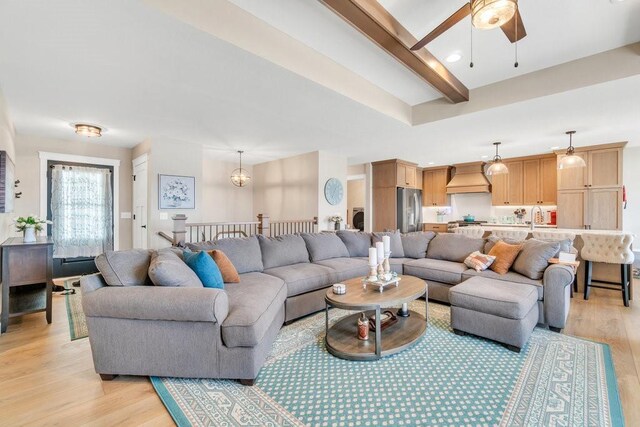 living room with beamed ceiling, light wood-style floors, and a ceiling fan