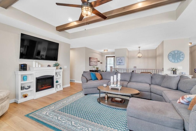 living room featuring light wood-style floors, baseboards, a ceiling fan, and beam ceiling