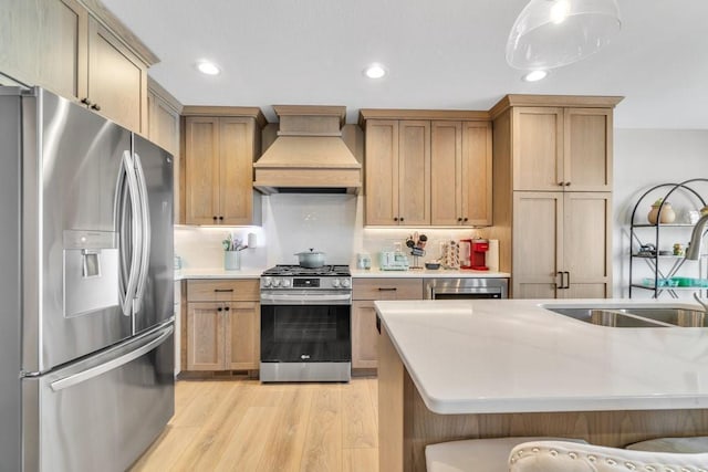 kitchen featuring light wood-type flooring, light countertops, a sink, stainless steel appliances, and premium range hood