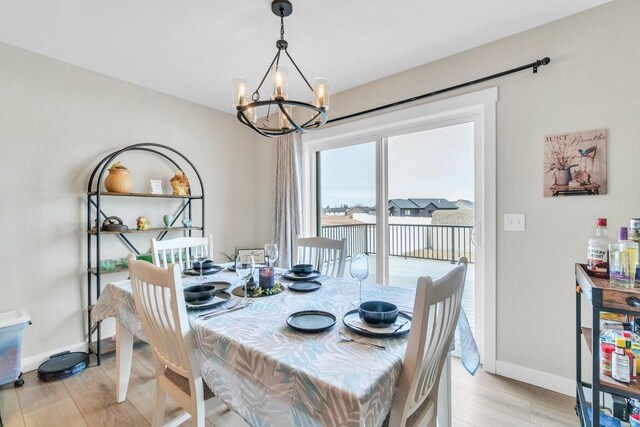 dining room featuring light wood-style flooring, a notable chandelier, and baseboards