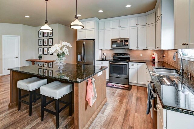 kitchen featuring decorative backsplash, stainless steel appliances, light wood finished floors, and a sink