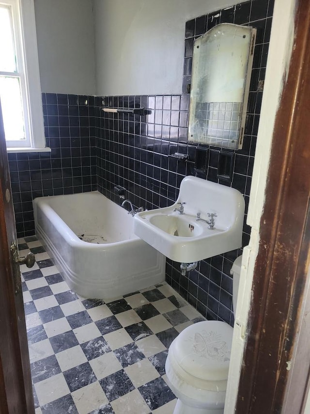 full bath with tile patterned floors, a tub, tile walls, and toilet