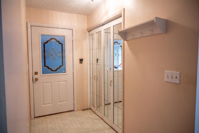 doorway to outside featuring a textured ceiling and light floors