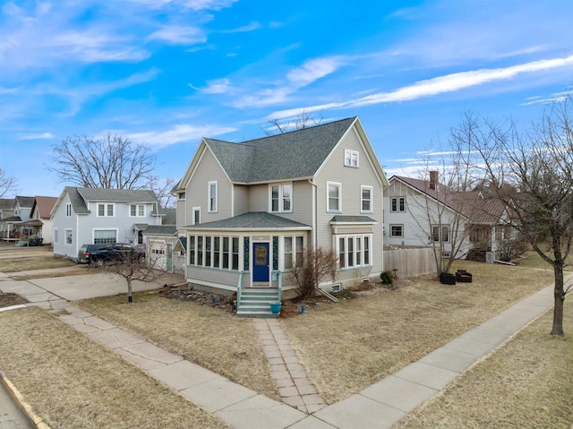view of front of house with fence, roof with shingles, and a sunroom