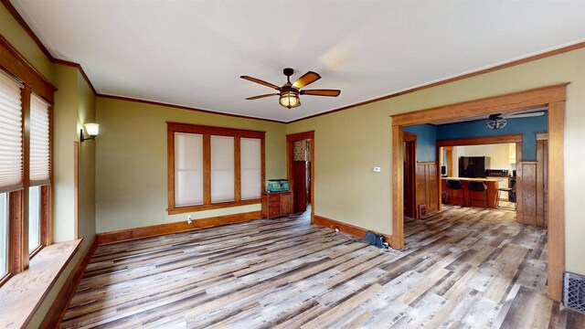 empty room featuring ornamental molding, ceiling fan, wood finished floors, and baseboards