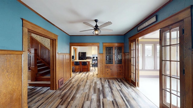 interior space with stairway, french doors, crown molding, a wainscoted wall, and wood finished floors