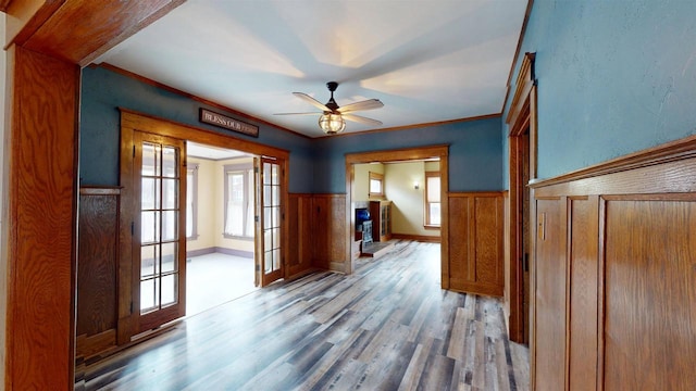 interior space featuring wainscoting, ceiling fan, crown molding, and wood finished floors