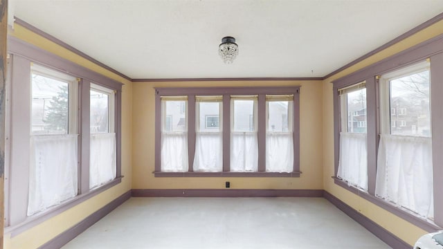unfurnished sunroom featuring ornamental molding and baseboards