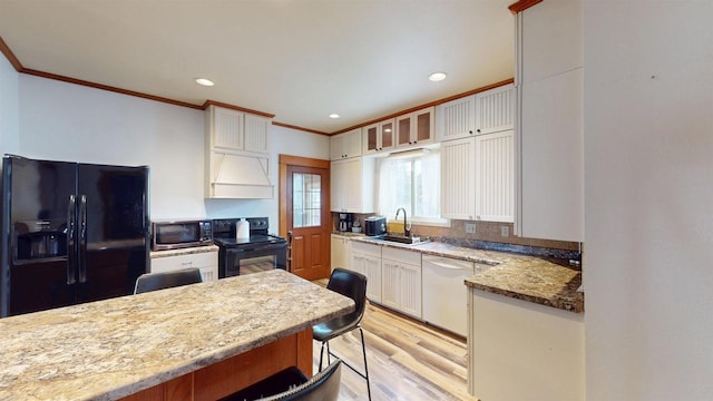 kitchen with white cabinets, a sink, light wood-style floors, crown molding, and black appliances