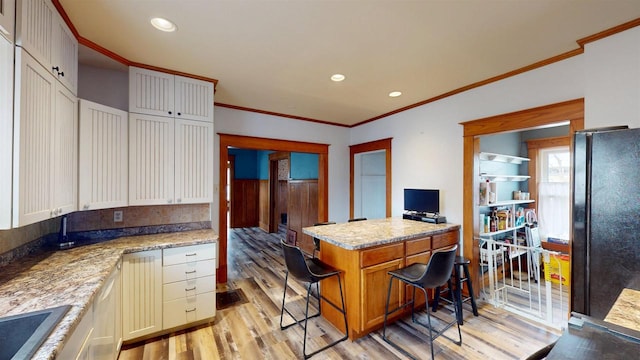 kitchen with ornamental molding, recessed lighting, freestanding refrigerator, light wood-style floors, and a sink