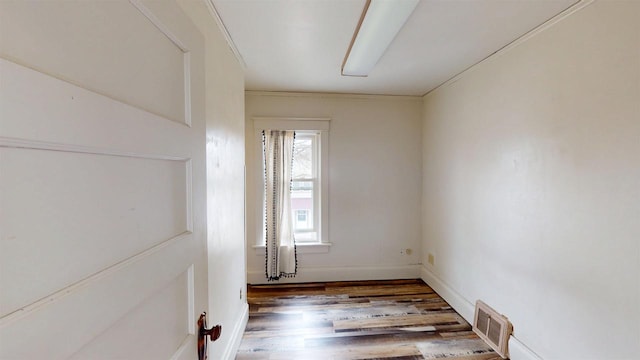 empty room featuring visible vents, baseboards, and wood finished floors