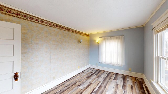 unfurnished room with wood finished floors, baseboards, and ornamental molding