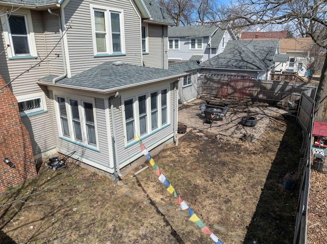 rear view of house featuring fence, a patio, and roof with shingles