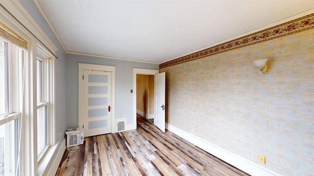 unfurnished room with crown molding, baseboards, a wealth of natural light, and wood finished floors