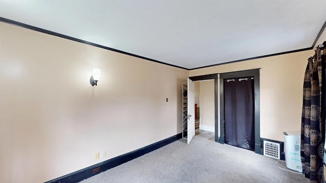 carpeted spare room with ornamental molding, baseboards, and visible vents