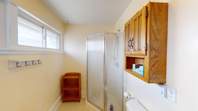 bathroom with toilet, a stall shower, and baseboards