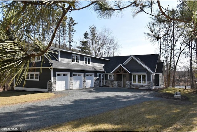 view of front of house with an attached garage, stone siding, and aphalt driveway