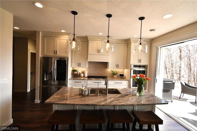 kitchen featuring stainless steel appliances, a kitchen breakfast bar, a sink, and backsplash