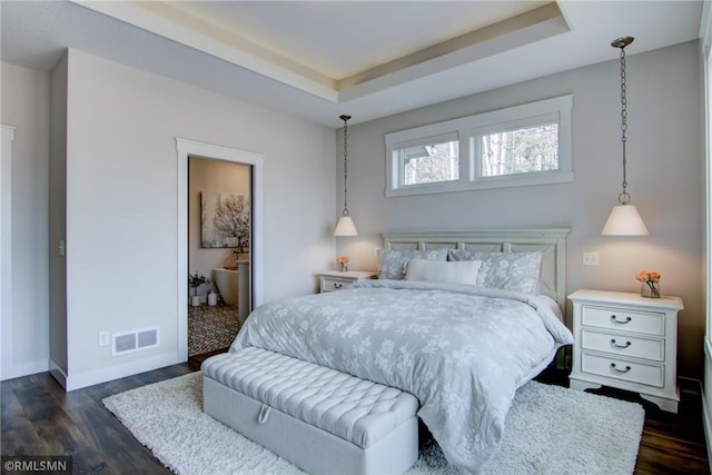 bedroom with dark wood-type flooring, visible vents, baseboards, and a tray ceiling