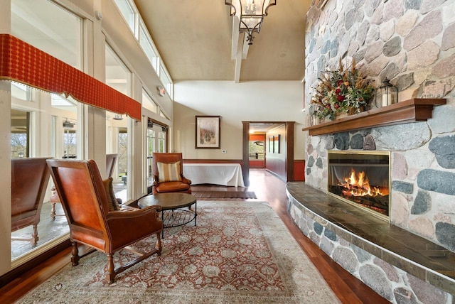 interior space featuring an inviting chandelier, a towering ceiling, wood finished floors, and a fireplace