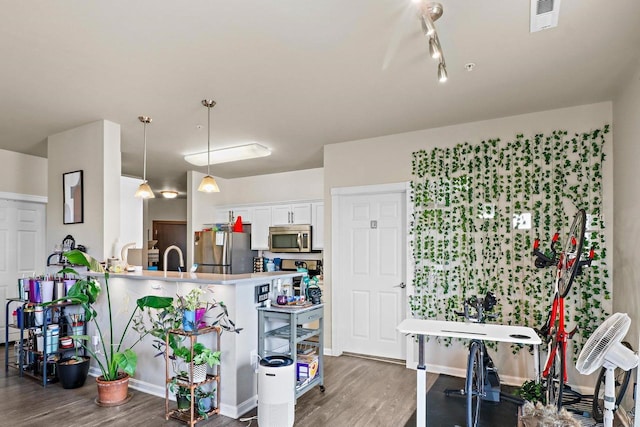 kitchen featuring white cabinets, visible vents, wood finished floors, stainless steel appliances, and hanging light fixtures