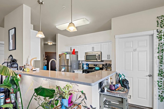 kitchen with a kitchen breakfast bar, a peninsula, white cabinets, stainless steel appliances, and hanging light fixtures