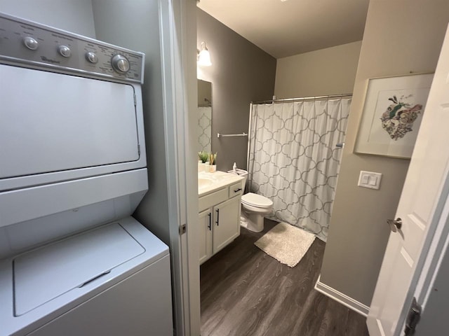 bathroom featuring vanity, curtained shower, toilet, stacked washer / drying machine, and wood finished floors