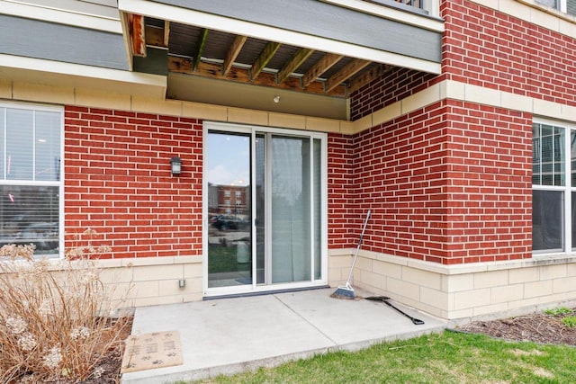 entrance to property featuring a patio area and brick siding