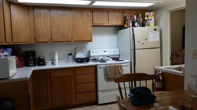 615 Congress St, Eau Claire, WI 54703 - kitchen with light tile patterned floors, white appliances, a sink, light countertops, and brown cabinets
