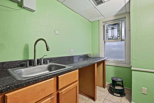 3316 W Wisconsin Ave, Milwaukee, WI 53208 - kitchen with dark countertops, light tile patterned flooring, brown cabinetry, a drop ceiling, and a sink