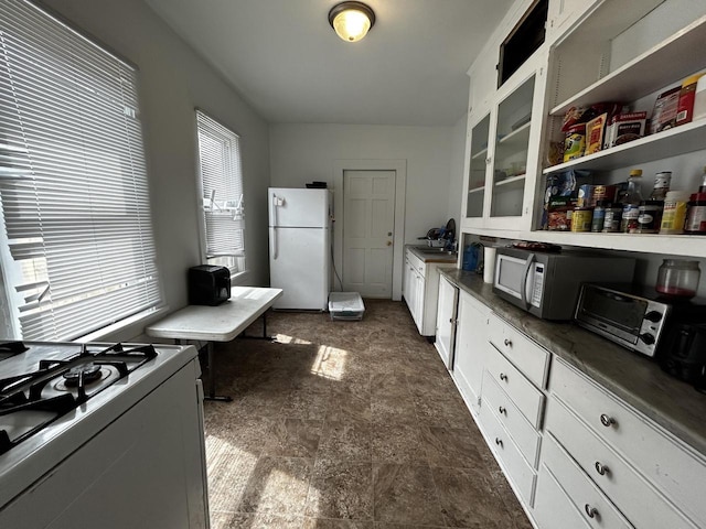 1842 Lasalle St, Racine, WI 53402 - interior space featuring freestanding refrigerator, glass insert cabinets, white cabinets, stone finish flooring, and gas stove