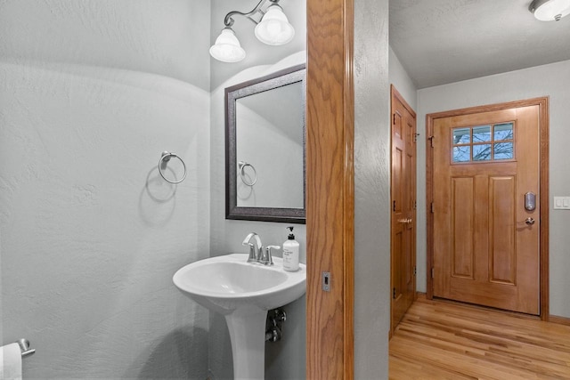 bathroom with wood finished floors and a textured wall