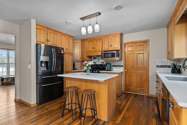 kitchen with a center island, light countertops, black appliances, dark wood finished floors, and a sink