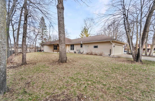 back of house featuring an attached garage, a yard, concrete driveway, and fence
