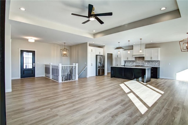 E5215 Queens Dr, Eleva, WI 54738 - unfurnished living room with a sink, light wood finished floors, a raised ceiling, recessed lighting, and a chandelier