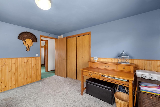 carpeted office space featuring wood walls and a wainscoted wall