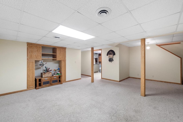 finished below grade area with light carpet, a paneled ceiling, baseboards, and visible vents