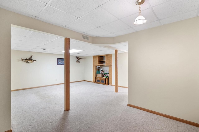 finished basement featuring visible vents, baseboards, a paneled ceiling, and carpet floors