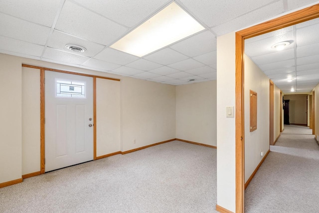 finished below grade area with a paneled ceiling, visible vents, baseboards, and carpet