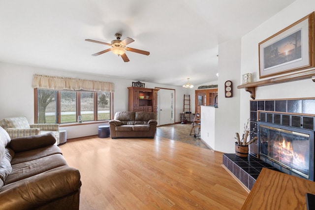 living area featuring wood finished floors, a fireplace, a ceiling fan, and vaulted ceiling