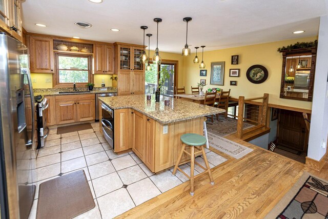 W340S2401 County Road C, Oconomowoc, WI 53066 - kitchen with light stone counters, a center island, visible vents, stainless steel appliances, and a sink