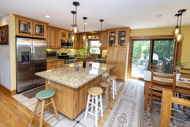 W340S2401 County Road C, Oconomowoc, WI 53066 - kitchen featuring a kitchen island, brown cabinets, a kitchen bar, stainless steel appliances, and a sink