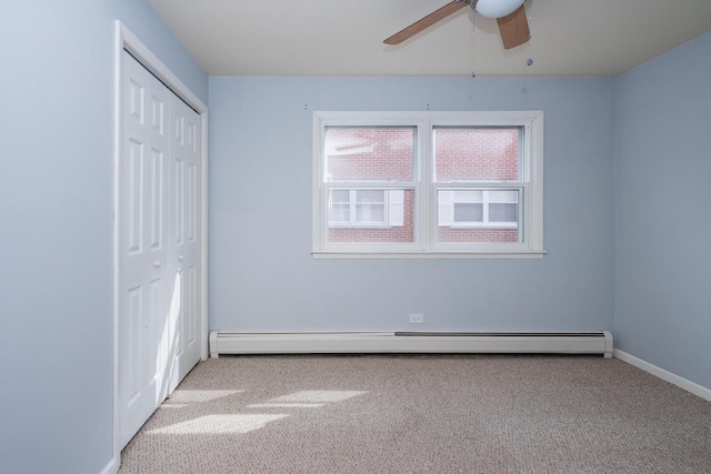 unfurnished bedroom featuring a closet, a baseboard heating unit, baseboards, and carpet flooring