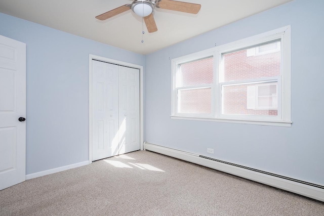 unfurnished bedroom with a closet, baseboards, a ceiling fan, carpet, and baseboard heating