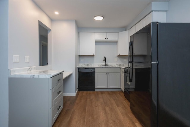 kitchen with a sink, dark wood-style flooring, light countertops, black appliances, and white cabinetry