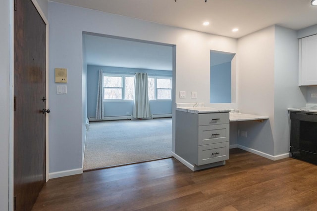 kitchen featuring built in desk, dark wood-style floors, light countertops, and baseboards