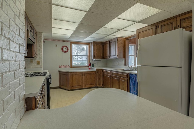 N1616 Haddinger Rd, Monroe, WI 53566 - kitchen with freestanding refrigerator, black range with gas stovetop, light countertops, a drop ceiling, and brown cabinetry