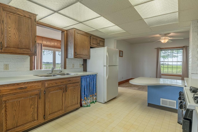 N1616 Haddinger Rd, Monroe, WI 53566 - kitchen featuring freestanding refrigerator, gas range, light countertops, brown cabinetry, and a drop ceiling