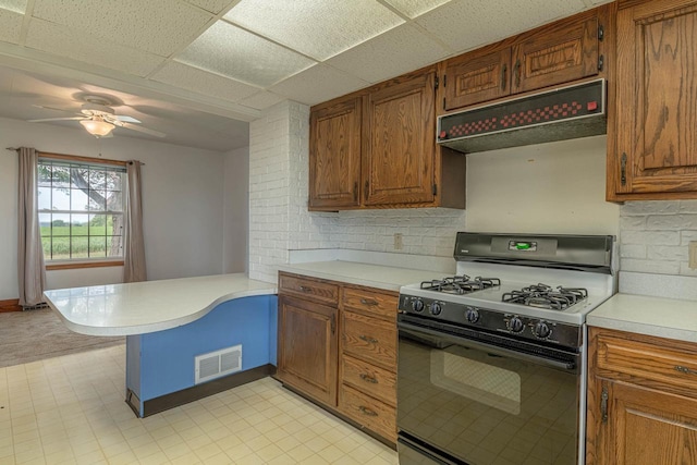 N1616 Haddinger Rd, Monroe, WI 53566 - kitchen featuring range with gas stovetop, under cabinet range hood, a peninsula, light countertops, and brown cabinets