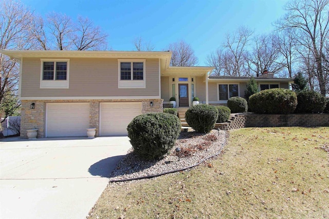 4786 Cardinal Ln, Sun Prairie, WI 53590 - tri-level home featuring concrete driveway, a front lawn, a chimney, stone siding, and a garage